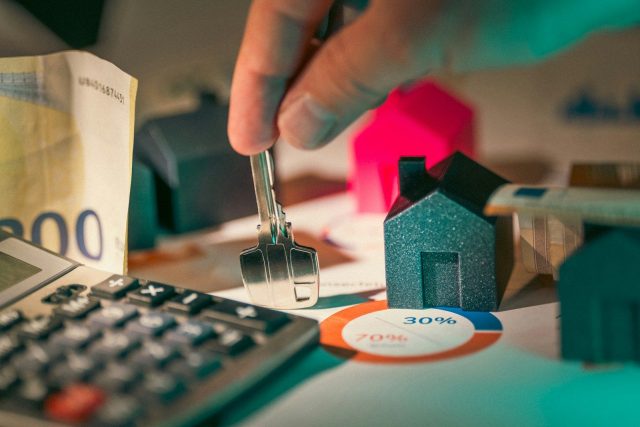 Photo by Jakub Żerdzicki hand holding key over house models