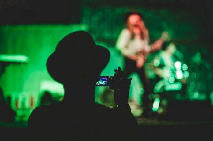 Photo by Francisco Moreno silhouette of man holding camcorder near woman singing on stage