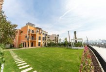 Wellness-Centric Luxury Property in Dubai: Homes Built for Mind & Body A luxurious building sits beside a vibrant green lawn.