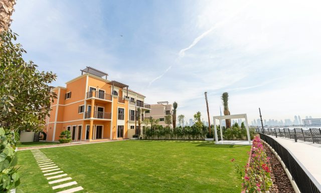 Wellness-Centric Luxury Property in Dubai: Homes Built for Mind & Body A luxurious building sits beside a vibrant green lawn.