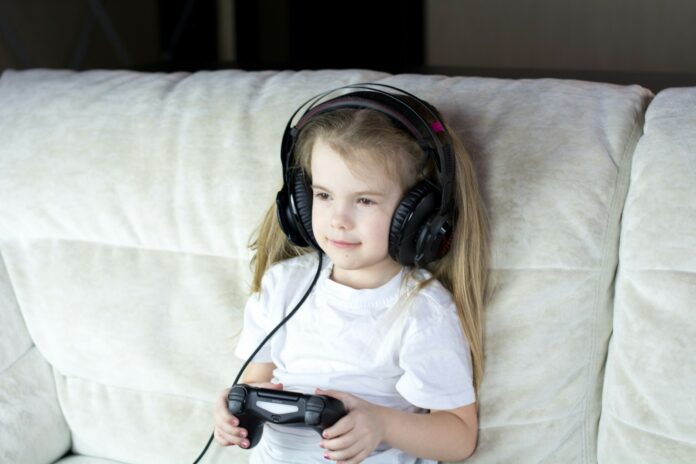 Photo by Bermix Studio a little girl sitting on a couch with headphones on