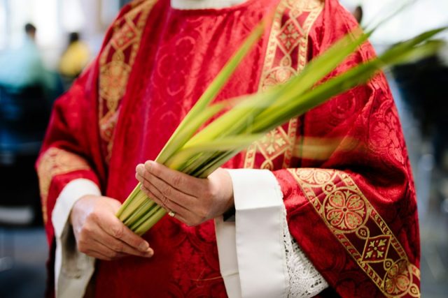 Photo by Grant Whitty priest holding palm leaves