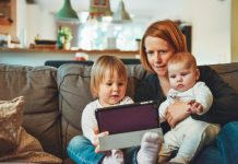 Crucial Factors to put in Mind When Buying a Home with Kids two babies and woman sitting on sofa while holding baby and watching on tablet