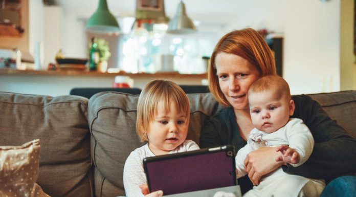 Crucial Factors to put in Mind When Buying a Home with Kids two babies and woman sitting on sofa while holding baby and watching on tablet