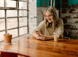 Stranger to Friend – Why OmeTV is the Best Social App a woman sitting at a table looking at her phone