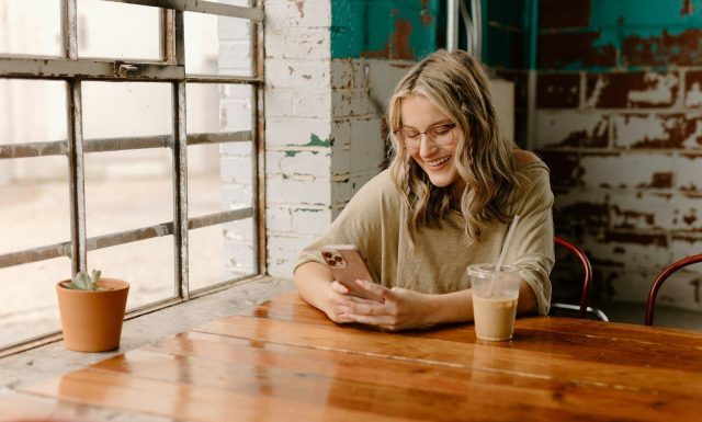 Stranger to Friend – Why OmeTV is the Best Social App a woman sitting at a table looking at her phone
