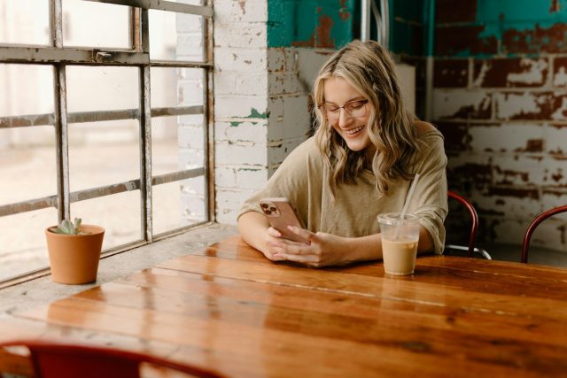 a woman sitting at a table looking at her phone